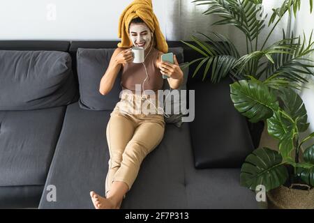 Young woman doing videocall with mobile smartphone while having skin care spa day at home Stock Photo