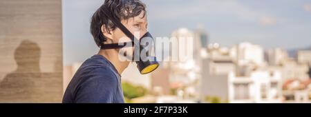 BANNER, LONG FORMAT Close up portrait of young man in respirator mask against the background of the city. Man puts on a respirator to protect himself Stock Photo