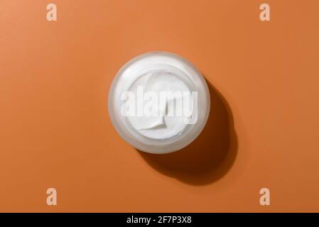 Glass skin cream jar on brown background Stock Photo