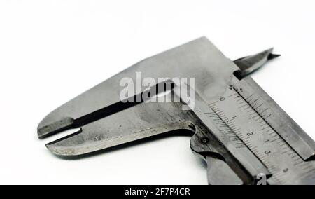 Detail view of a metallic caliper used to measure the distance between two opposite sides of an object. Engineering and construction industry. Isolate Stock Photo