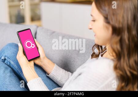Kyiv, Ukraine - April 2, 2021: Google Fuchsia OS logo on the mobile phone screen. A woman is holding smartphone with Fuchsia logo on the display, operating system developed by Google Corporation Stock Photo