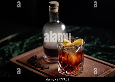 A beautiful Old Fashioned cocktail served with coffee-infused aged rum over ice on a rock glass. The cocktail is presented in a bottle with smoke Stock Photo