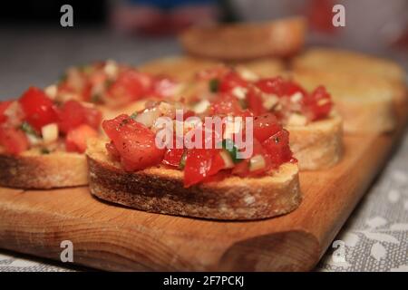 Bruschetta with tomato, basil garlic on wooden board. Stock Photo