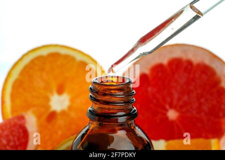 Pipette dripping oil in bottle against citrus, isolated on white background Stock Photo