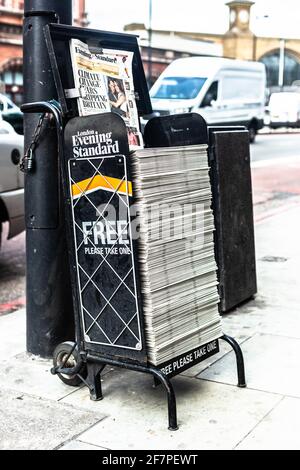 Evening Standard free newspaper stand chain to a pavement post, London, England, UK. Stock Photo