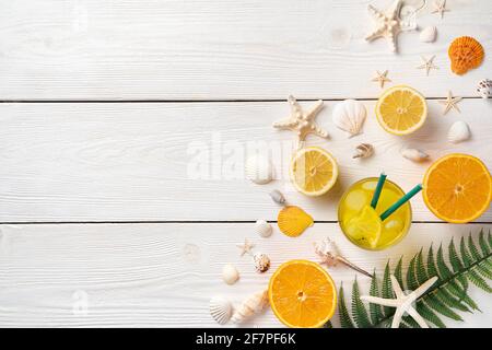 Citrus fruits, iced cocktail, seashells and starfish on a white wooden background. Summer background with copy space. Stock Photo