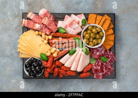 Meat appetizer, cheese and olives on a rectangular cutting board. Top view, horizontal. Stock Photo