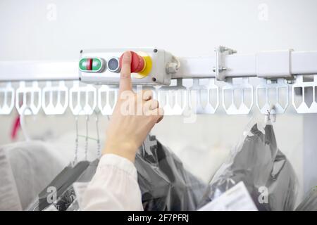 Womans finger is on start button of clothes rack Stock Photo