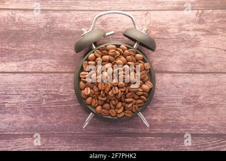 top view of fresh coffee beans and alarm clock on wooden table  Stock Photo