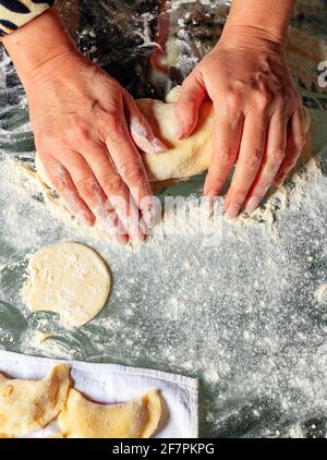 Women's hands knead dough for making vareniki according to Ukrainian national cuisine. Stock Photo