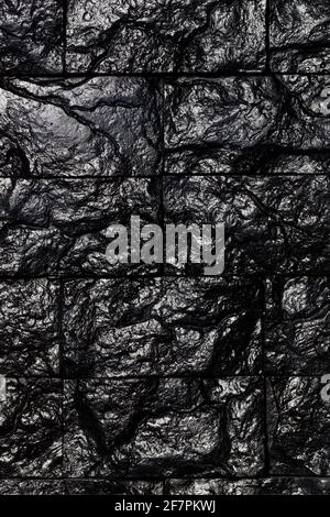 Textured rectangular decorative tiles of black coal, as an unusual interior texture and background. Vertical image. Stock Photo