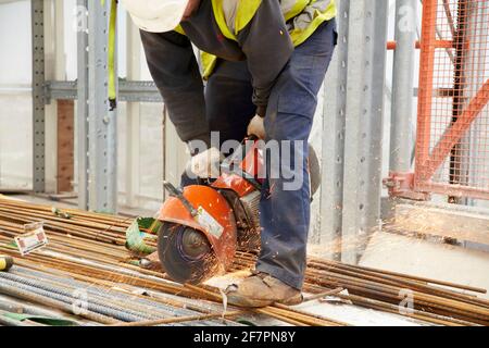 Construction worker using angle grinder during concrete pour for tower block Stock Photo