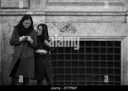 two people at the bus stop, on the street., Rome, Italy Stock Photo