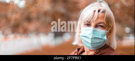 Coronavirus, COVID-19 Pandemic concept. Blonde woman in wearing face mask protective for disease virus SARS-CoV-2 at the city street Stock Photo