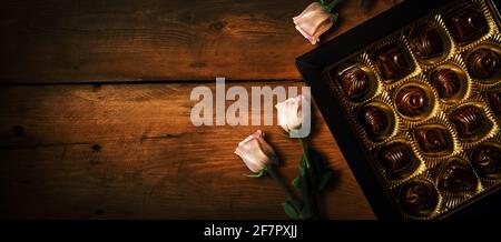 romantic gift - chocolate candy box with rose flowers on old wooden background. banner copy space Stock Photo