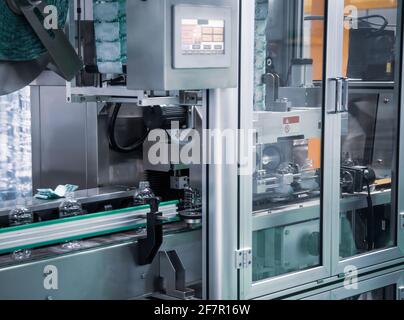 Process of PET plastic bottle on automatic sleeve labeling machine Stock Photo