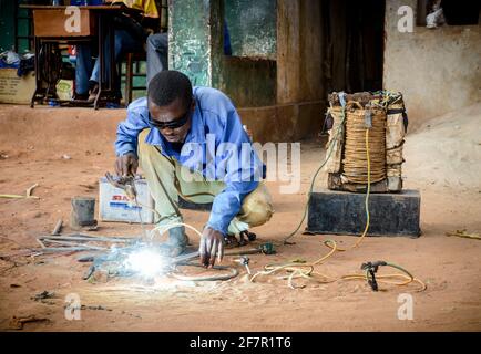 Man in street scene in Malawi village with crude welding set Stock Photo