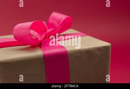 Gift box wrapped in craft paper with ribbon on bright background Stock Photo