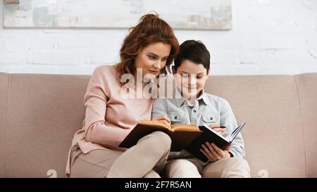 Mother and son reading book during home education Stock Photo