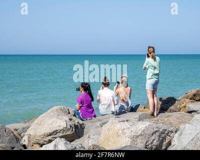 Girls sitting on rocks at the Jetty in Venice Florida on the Gulf of Mexico in the USA Stock Photo