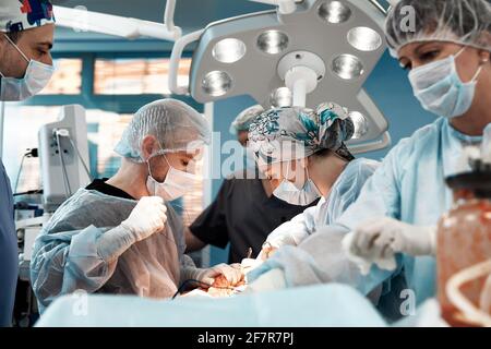 Doctors performing abdominoplasty surgery in the hospital. Focus on male plastic surgeon doing abdominal plastic surgery in operating room. Concept of Stock Photo