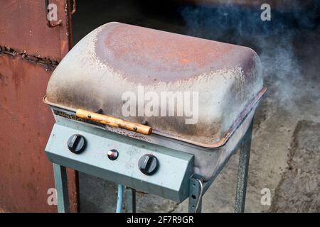 Rusty barbecue lit with closed lid and smoke coming out Stock Photo