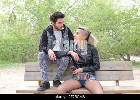 Young punk couple in a park blowing bubble gum. Rock and roll lifestyle. Stock Photo