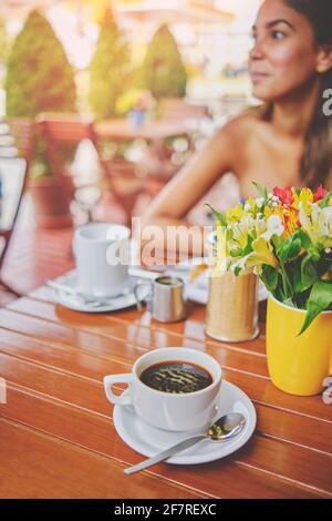 Couple sharing in a cafeteria at sunset, romantic moment with flowers, coffee and vintage site Stock Photo