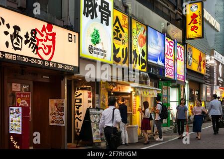 Horizontal view of a row of fast foods and restaurants plenty of colorful neon signs on Shibuya Center-gai, Shibuya, Tokyo, Japan Stock Photo