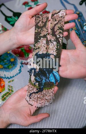 Weaving from beads. Close-up - hands of women with ready-made beads. The woman is fond of weaving from beads. Stock Photo