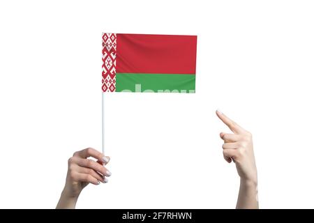 A beautiful female hand holds a Belarus flag to which she shows the finger of her other hand, isolated on white background. Stock Photo