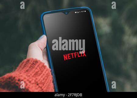 Podolsk, Ukraine - March 29, 2021: Woman holding smartphone with app Netflix on the screen Stock Photo