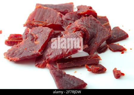 High protein diet and food that is high in sodium and salt concept theme with close up on beef jerky meat strips isolated on white background Stock Photo