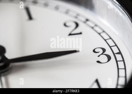 Clock hand pointing three o'clock on white clock face of Twin bell classic alarm clock Stock Photo