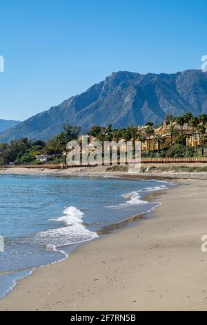 a spring walk along one of the many beaches located in Marbella with mountains surrounding the town in the background Stock Photo