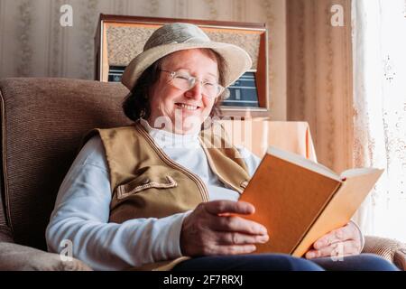 Elderly woman with a hat on, reading a 