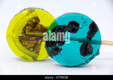 Lollipop with black currant inside turquoise color and lollipop with yellow lemon slice on a white background. Stock Photo