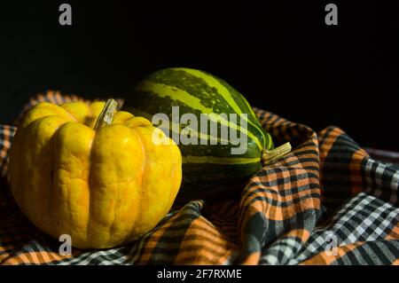 Small pumpkins on a dark food style checkered cloth, with dark background and copy space Stock Photo