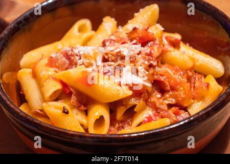 Penne all Arrabiata Pasta or Noodle Dish with Parmesan Cheese on a Rustic Table Stock Photo