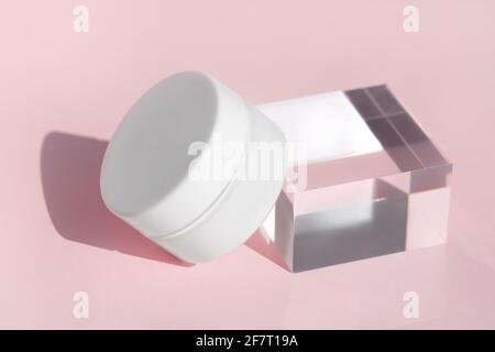 Luxury face cream cosmetic mock up on transparent solid block. Blank jar of organic lotion, medical balm standing on glass cube podium pedestal Stock Photo