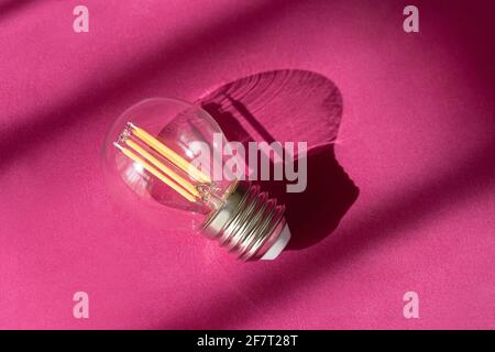 Light bulb on purple background with shadows close up. Creative new idea, innovation, inspiration concept. Stock Photo
