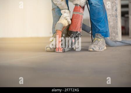 Worker working on the floor of an industrial building. Construction worker producing grout and finishing wet concrete floor. Stock Photo