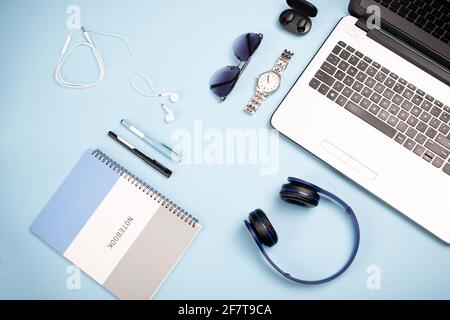Notebook, notepad, headphones, earphones, pens, watch, sunglasses on a blue background Stock Photo