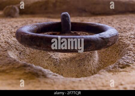 Detail of an old rusty iron ring hanging on a stone wall Stock Photo