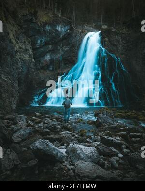 man with backpack standing in front of waterfall Stock Photo