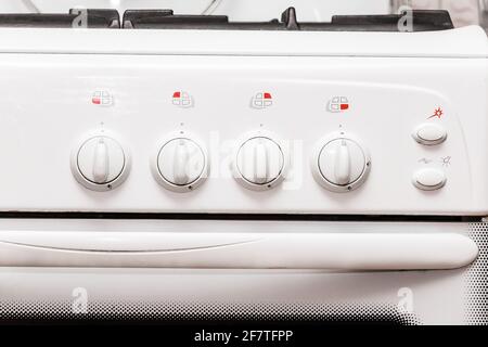 Frontal view of a white gas stove with burner control buttons, close up. Stock Photo