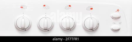 Frontal view of a white gas stove with burner control buttons, close up. Stock Photo