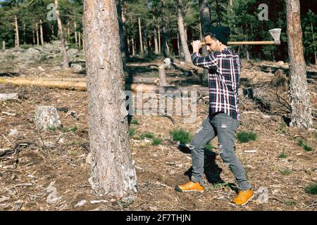 Lumberjack man chopping wood with an ax in the forest Stock Photo