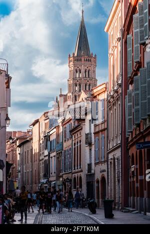 Toulouse, Occitania, France; July 21, 2018: The bell tower of the cathedral over the buildings of Taur street  with the last lights of the evening Stock Photo