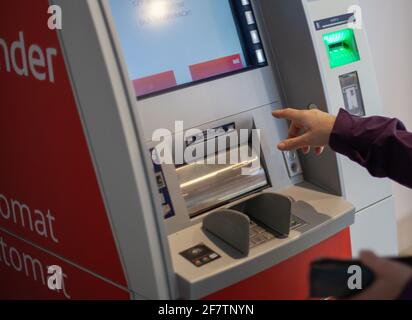 LESZNO, POLAND - Apr 01, 2021: Women withdrawing money from ATM.  Woman's hand Stock Photo